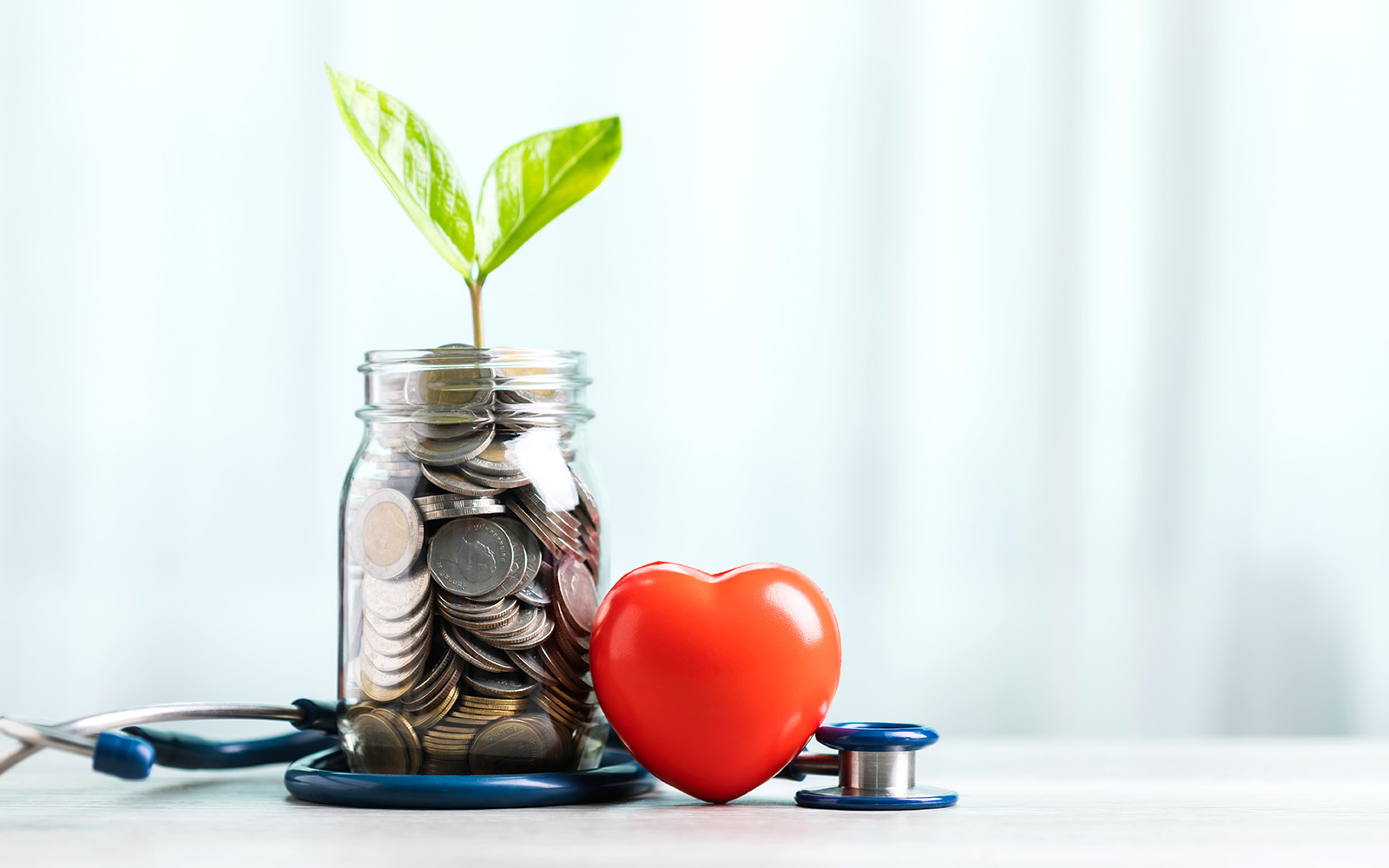 Jar filled with coins set next to a stethoscope. 