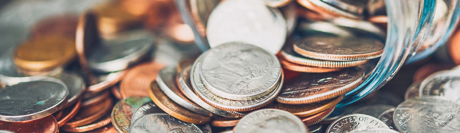 Coins spilling out of a glass jar.