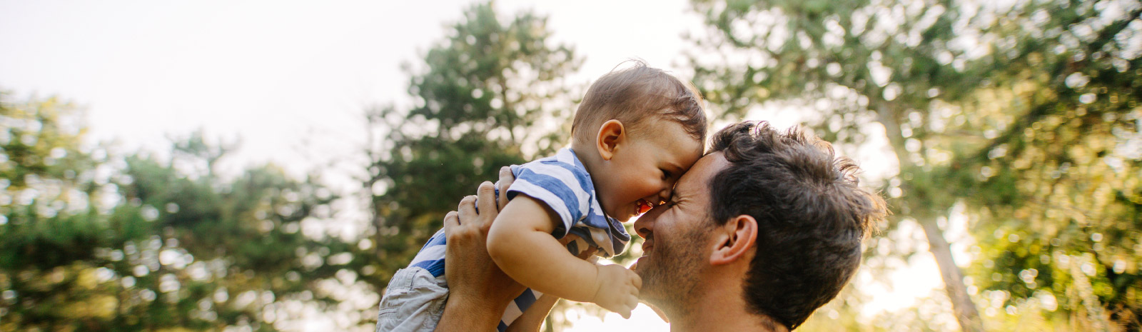 Father holding young son outdoors.