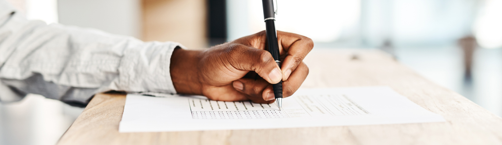 a person's hand writing on a paper form