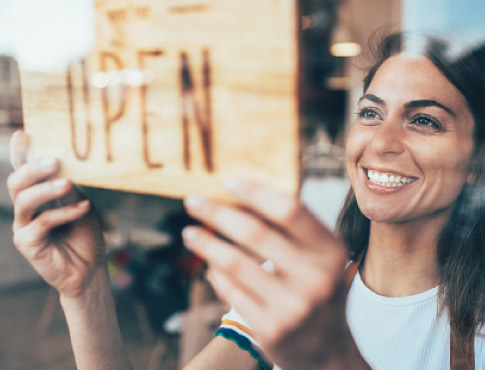 Small business owner joyfully setting open sign.