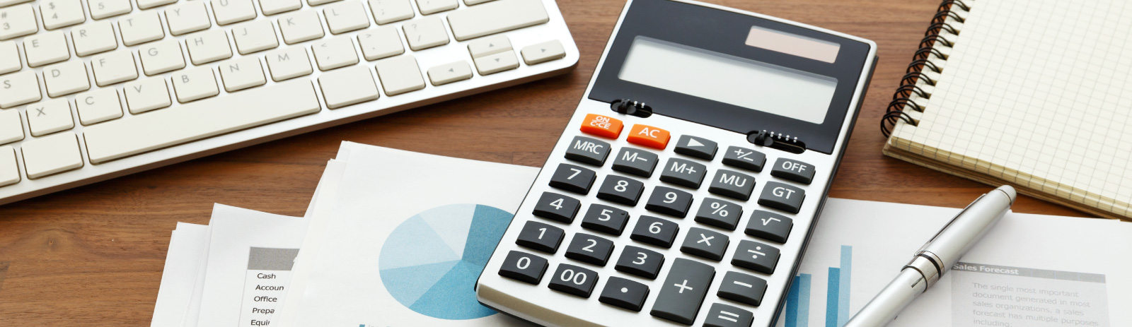 calculator next to a keyboard, pen and documents