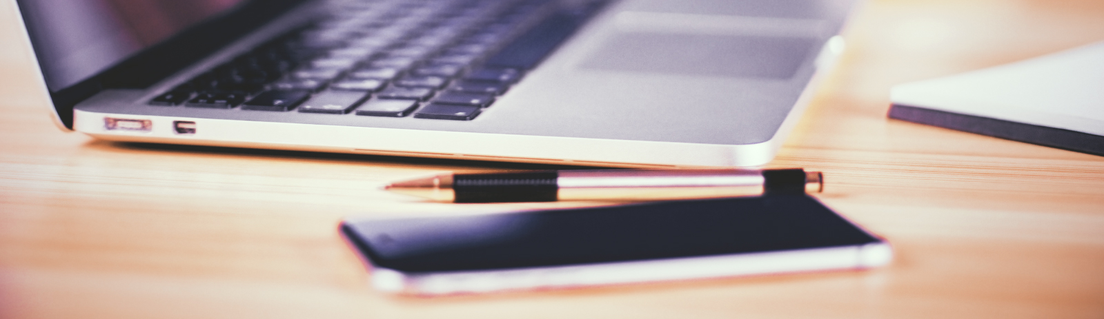 a mobile device placed next to a pen and laptop